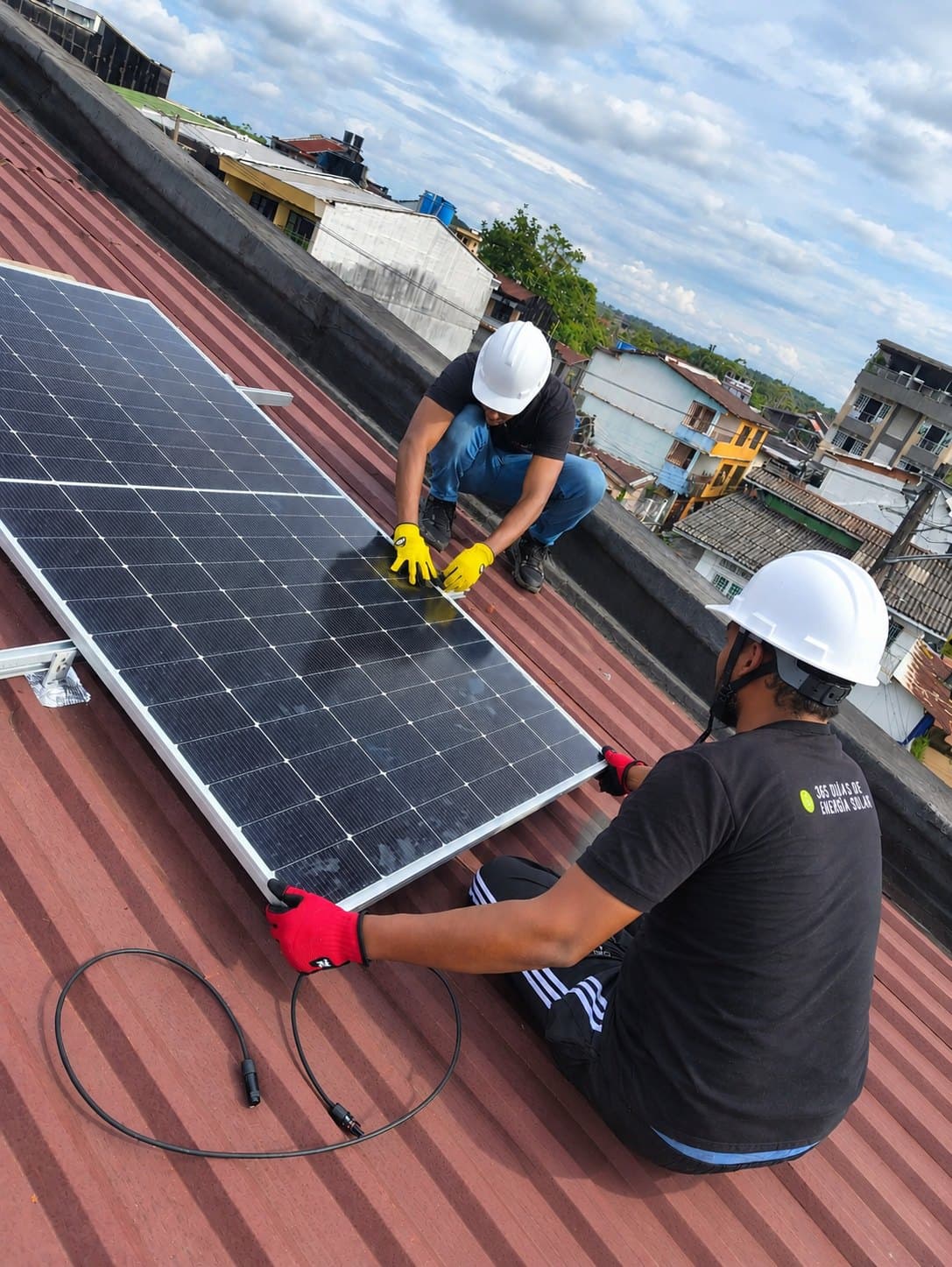 Dos técnicos de Sunset con casco colocando un panel solar sobre un tejado de teja roja
