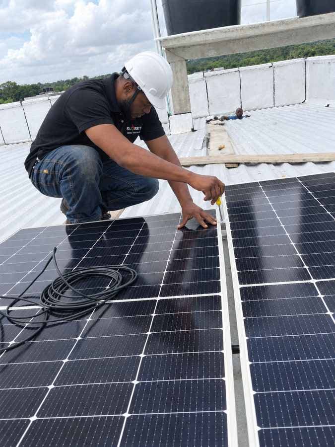 Técnico con casco verificando una instalación de paneles solares en cubierta