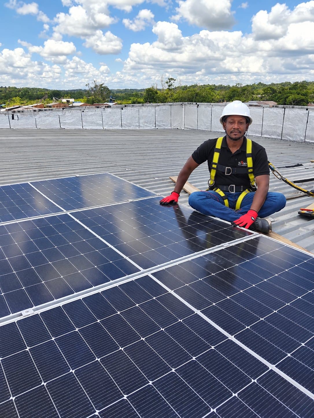 Instalador con arnés sobre paneles fotovoltaicos en una cubierta amplia